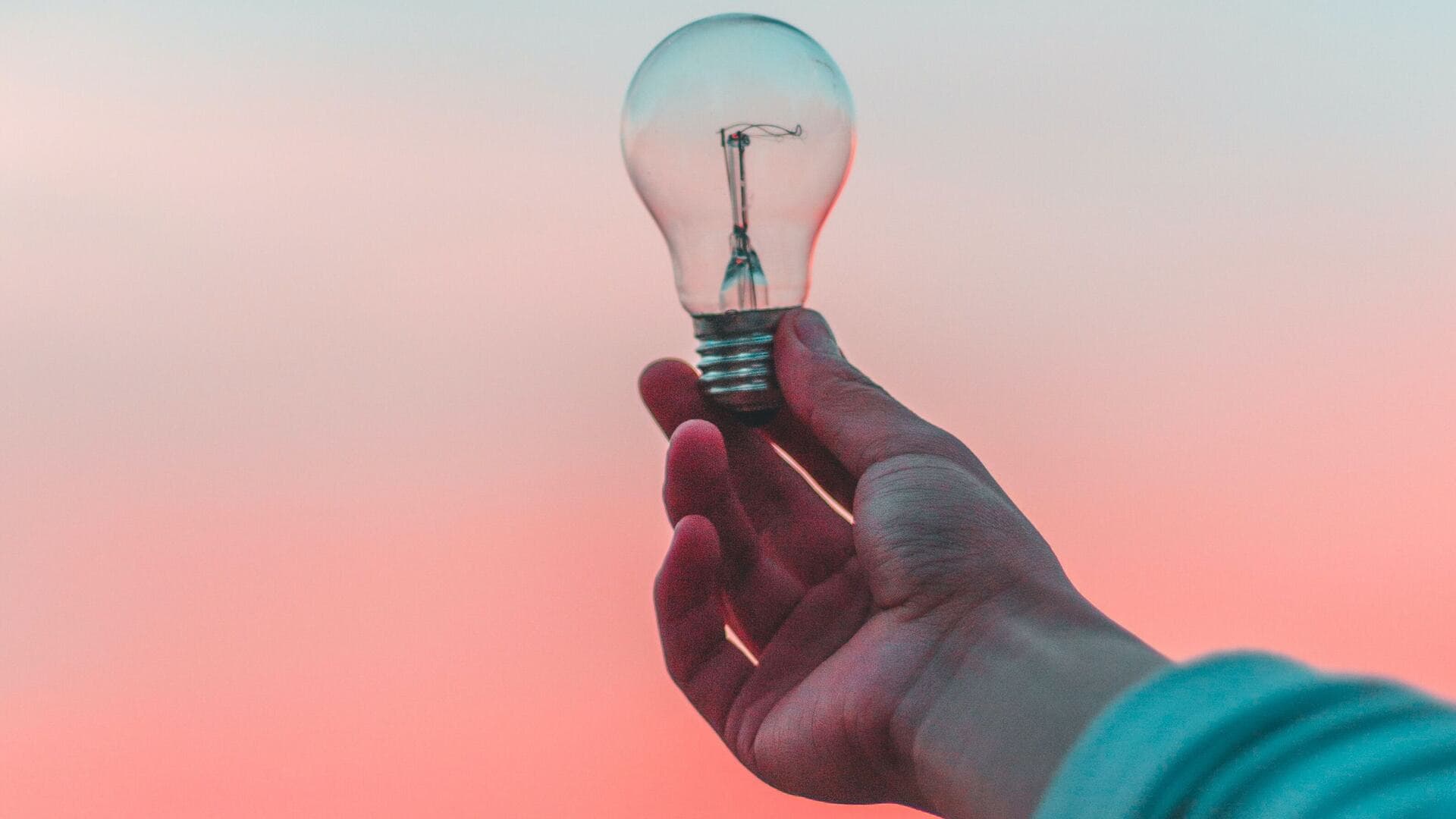 A hand holding a lightbulb represents the challenge of establishing product value in the customer’s mind.